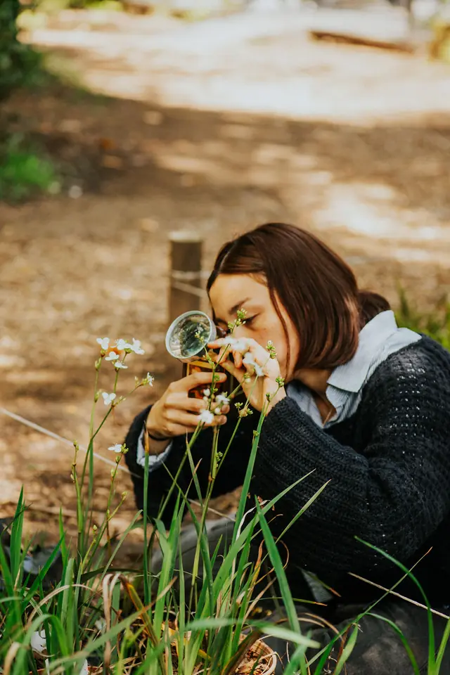 Niña observa una planta con una lupa