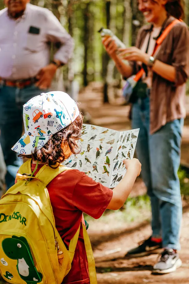 Niño con jockey mira una lámina de plantas durante un recorrido